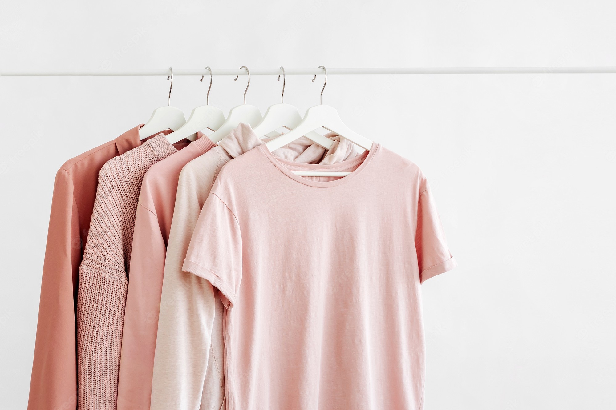 Premium Photo | Feminine clothes in pastel pink color on hanger on white background. spring cleaning home wardrobe. minimal fashion concept.